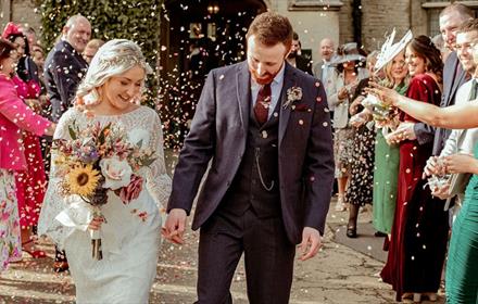 Wedding guests throwing confetti over newly married couple.