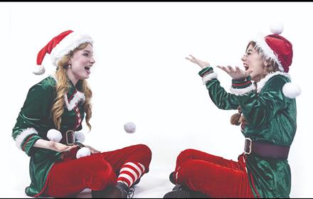 Two elves laughing and playing with a snowball.