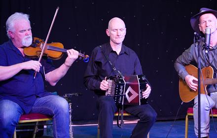 Members of the Roisin Ban Ceili Band performing on stage.