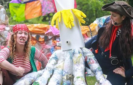 Two pirates stand next to a sea creature made from rubbish.