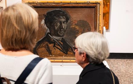 Two people admiring Norman Cornish's artwork.