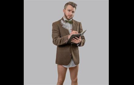 Phil Green writing in a notebook, wearing a suit (top half) minus trousers.