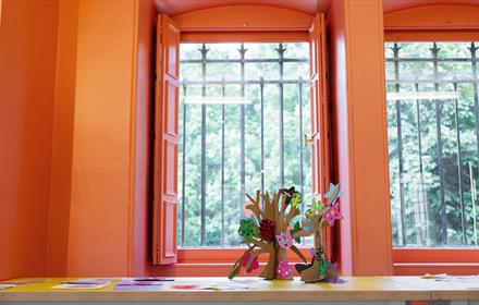 Flowers in front of a window that leads to a view of trees.