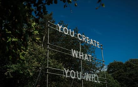 ©TheBowesMuseum
A structure in front of the trees with the words, 'You Create What You Will'.