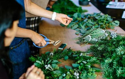 People making wreathes from festive greenery.