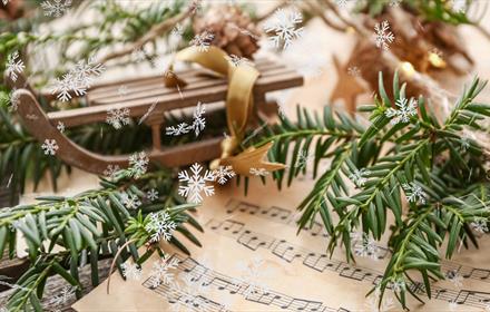 Sheet music with festive greenery on top.