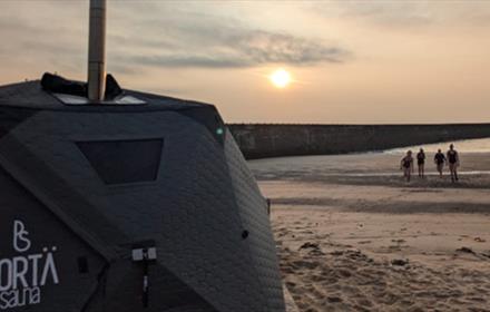 Beachgoers at sunrise on the beach in Seaham heading to the sauna
