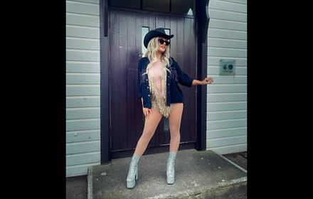 Taylor Swift lookalike in a cowgirl hat and silver platforms.