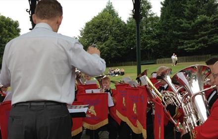 A brass band performing in the 1900s Town Bandstand at Beamish Museum with crowds watching.