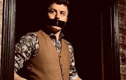 Tom Bolton with tape over his mouth.