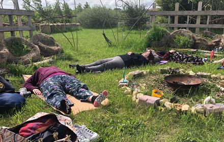 People lying in the grass at Dalton Moor Farm enjoying a Mindful Morning