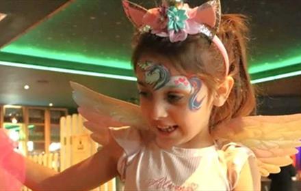 Little girl with fairy wings and a unicorn painted on her forehead