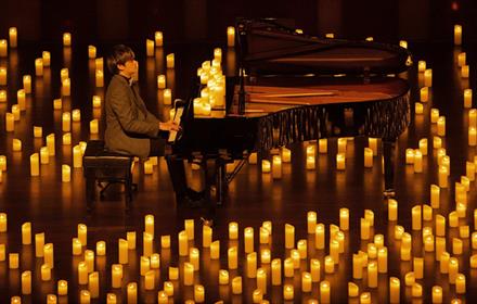 Pianist performing amongst hundreds of candles.
