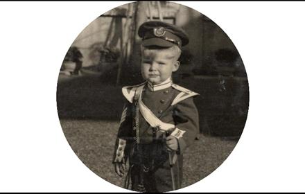 Black and white photo of a child in military clothing.