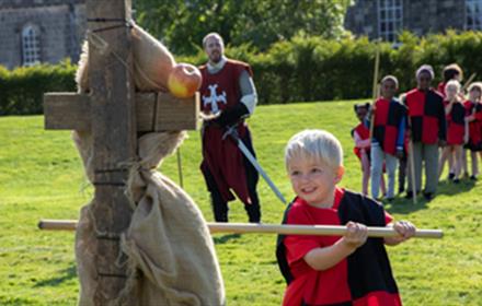 Children dressed as knights, holding wooden weapons.