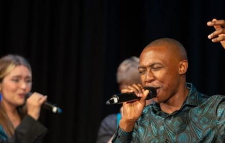 Three people singing on stage.