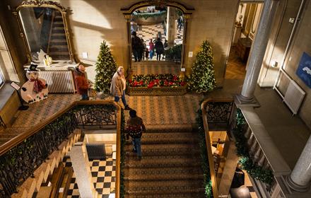 Staircase at The Bowes Museum decorated with Christmas trees.