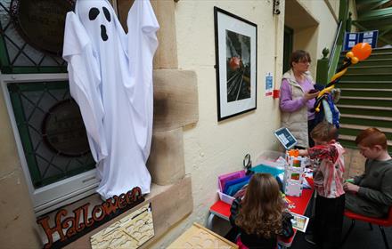 Children at a BrickLab workshop at Hopetown Darlington. A spooky ghost hangs over them on the wall.