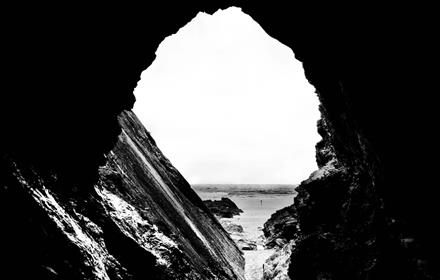 Black and white image of a cave opening out to sea.