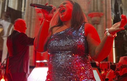 Performer in a sparkly dress singing 'The Music of Bond' at Durham Cathedral.