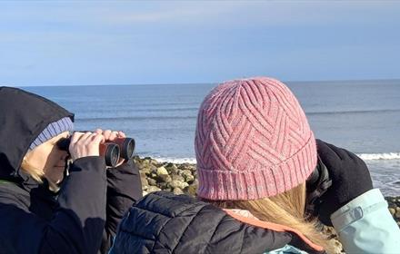 Birdwatchers peering out to see with binoculars on a chilly day.