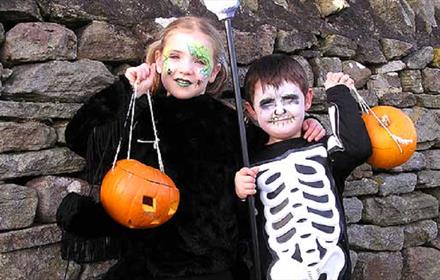 Children dressed as skeletons and holding pumpkin lanterns at Hall Hill Farm