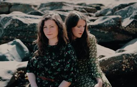 Two members of the act, 'The Unthanks' sitting on some rocks.