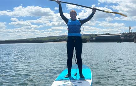SUP paddleboarder on the water with oar held above her head