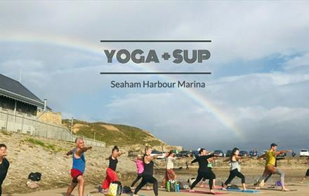 A Yoga and SUP session taking place under a rainbow at Seaham Harbour Marina.