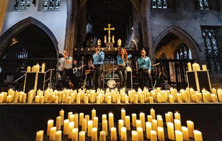 Singers performing surrounded by candles at Durham Cathedral.