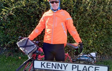 Ken Bradshaw with his bike outside of a street named 'Kenny Place'