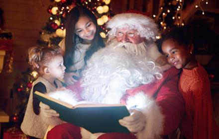 Santa reading three children a story.