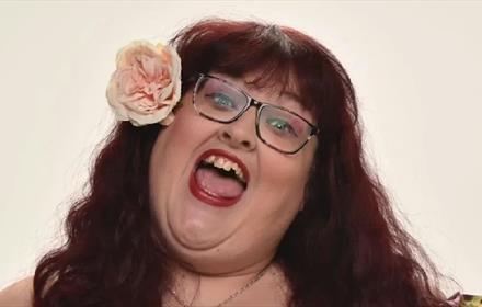 Headshot of Charlotte Forman with a flower in her hair (professional singer and comic).