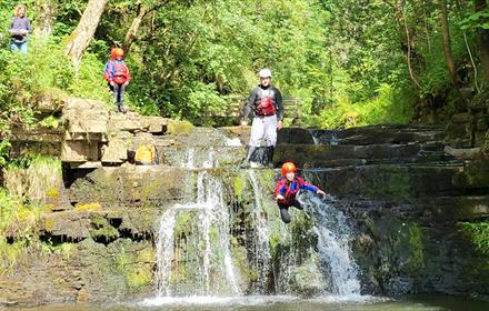 A group enjoying climbing waterfalls, navigating rocky streams and plunging into deep pools.
