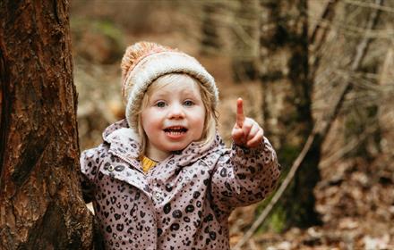 A child smiling and pointing upwards.