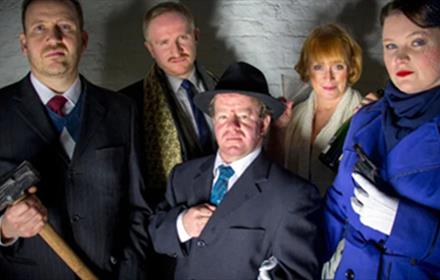 5 murder mystery participants in traditional clothing, one holding a hammer.