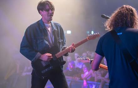 Jonny, lead singer of Sham Fender, and a band member performing to an audience.