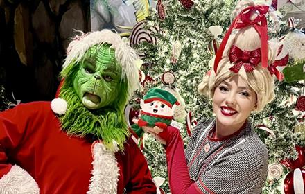 Mr. Grinch and Cindy-Lou posing for a photo in front of a Christmas tree at Lanchester Garden Centre.
