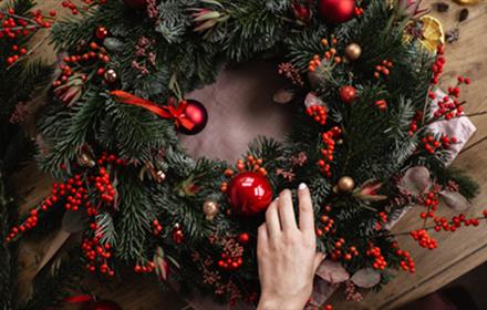 A handmade wreath with red berries and baubles.