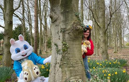 Easter bunny and woman with bunny ears hiding in woods