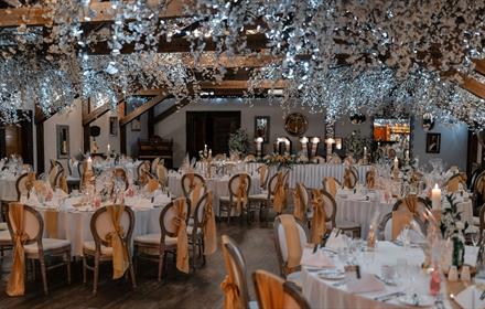 Tables and chairs dressed beautifully in white, with flowers and fairy lights,  for a wedding at South Causey Inn