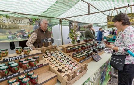 Chutney trader. Woman looking at stall and holding purse.