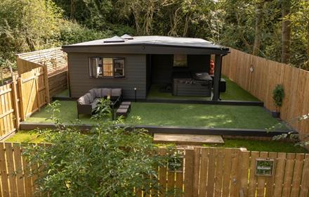 Exterior image of 'The Oak', Beamish Glamping, in a woodland location, showing the outdoor seating area.