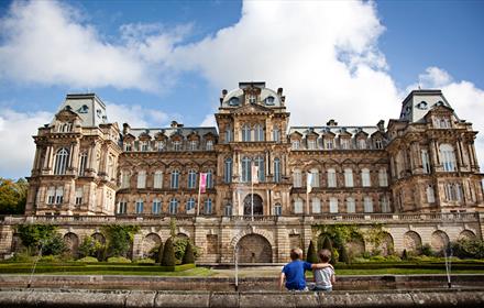 Two boys sat with their backs to the camera looking at the front of The Bowes Museum.