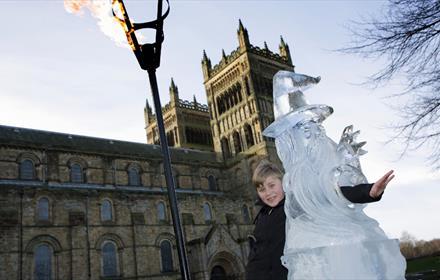 child poses with ice culture and flame lit torch outside Durham Cathedral.