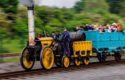 Locomotive pulling a coach pulling a crowd of people