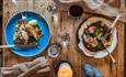 Image of a table set for two showing delicious meals, wine and candles.