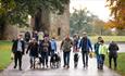 group of people walking dogs with Raby Castle in the background.