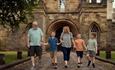 A family walking in front of the gateway of Durham Castle