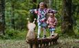 Two children playing on wooden sculpture.